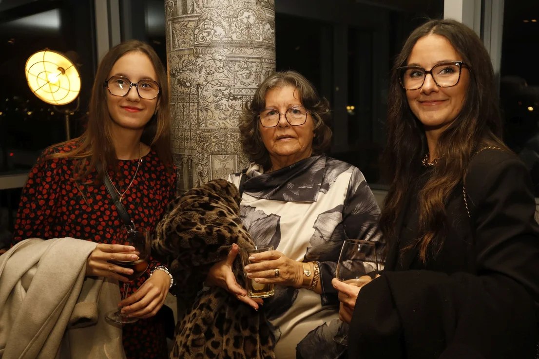Tres asistentes posan junto a una columna del salón.